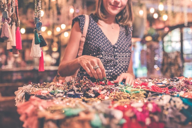 woman at an Indian market looking through malas and other jewelry 